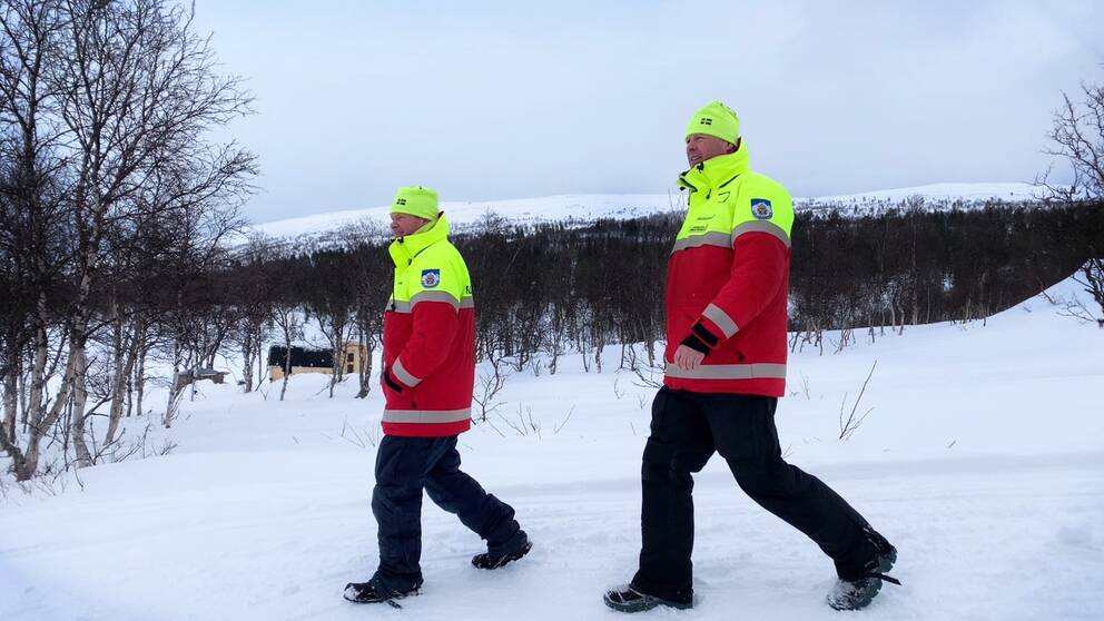 Fjällräddarna Mikael Westerdal och Stefan Korssjön går sida vid sida ner mot Grövelsjön. Det är vinter.