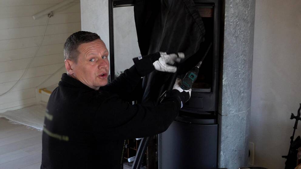 Skorstensfejaren Johan Kaijser utför en stavsotning av en braskamin.