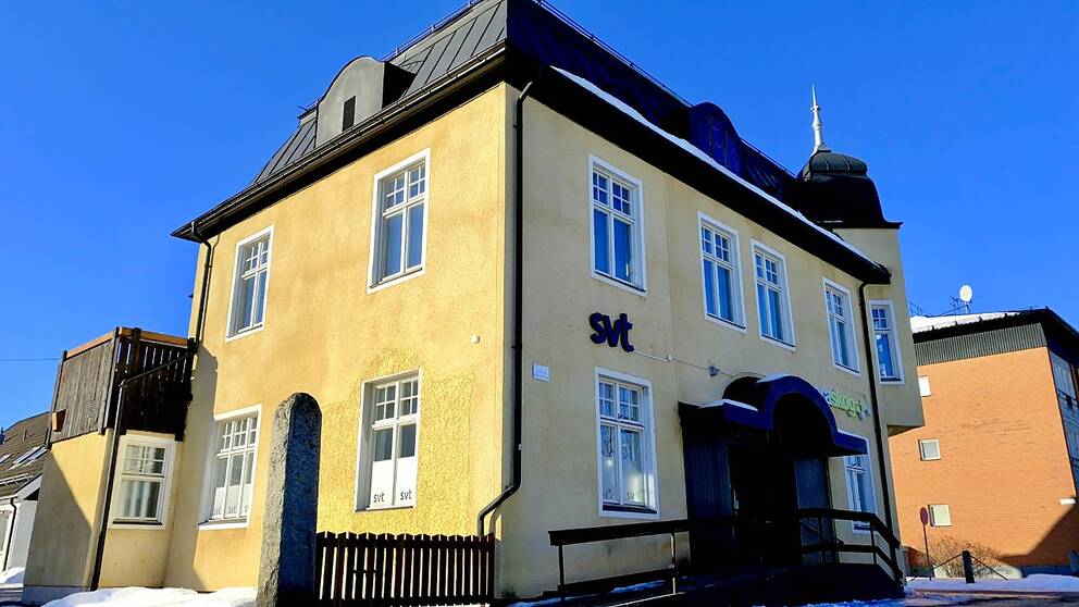 bilr på ett gult rappat hus med skylten SVT på sidan.