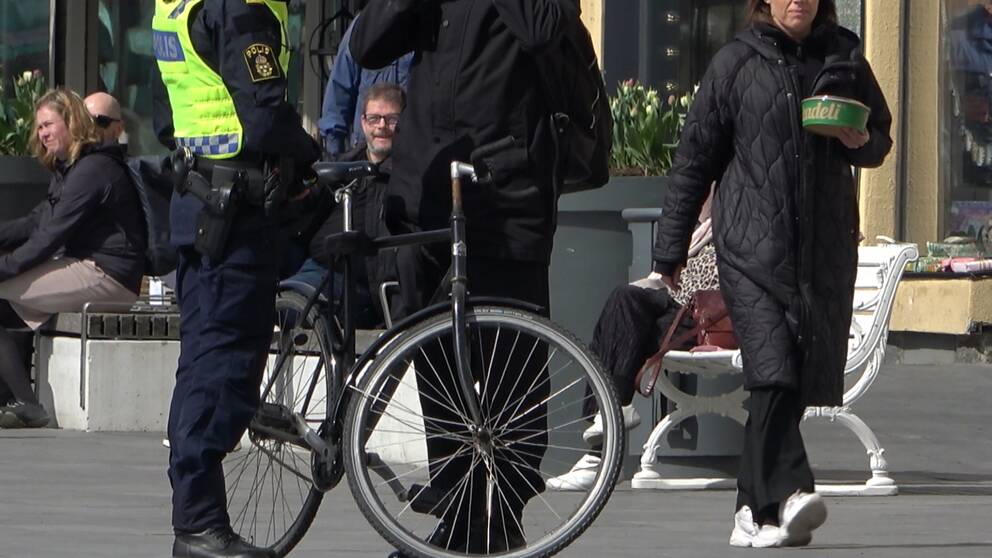 Polis som pratar med en person som håller i sin cykel.