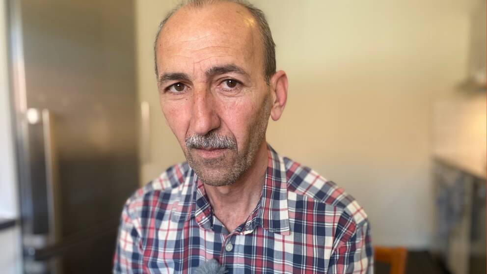 Porträttbild på Salim Abdal. Han tittar in i kameran och har på sig en rutig skjorta i vitt, blått och rött.
