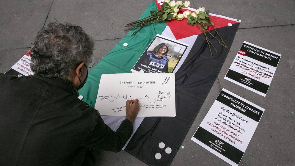 En man skriver ett meddelande till den palestinsk-amerikanska journalisten Shireen Abu Akleh under ett minnesmärke och en demonstration till hennes ära utanför The New York Times kontorsbyggnad i New York, USA på fredagen.