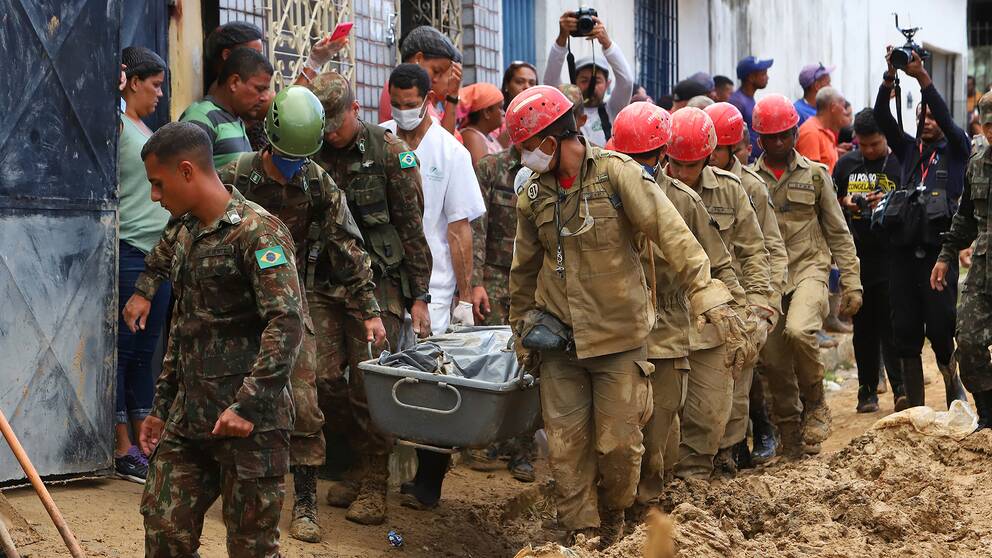Brandmän och soldater bär bort ett av de dödsoffer som omkommit i lerskreden i Pernambuco.