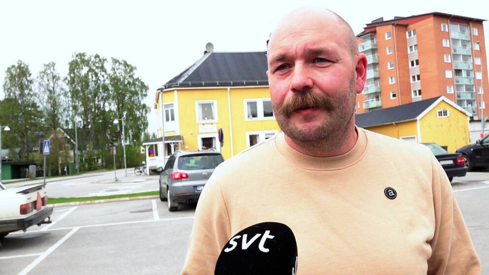 en medelålders man med mustasch intervjuas på en parkering