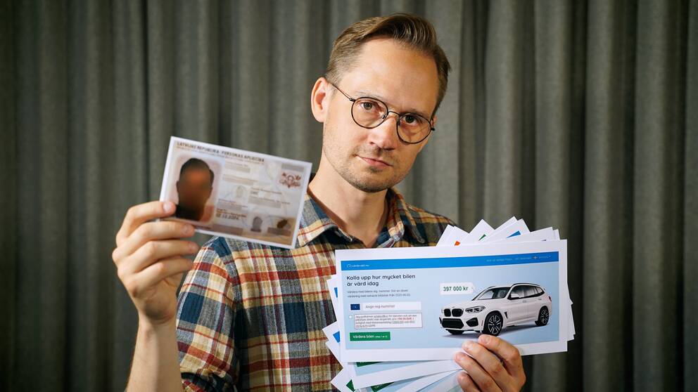 En person håller upp lappar med reklam för bilvärderingsfirmor. 
