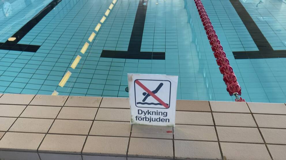 En skylt som det står ”dykning förbjuden” på med en bassäng i bakgrunden.