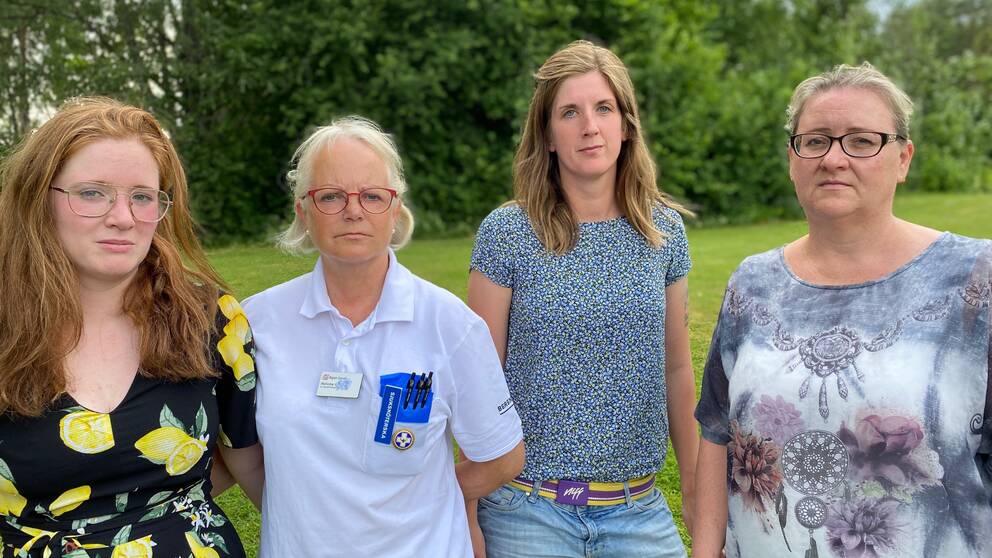Fyra kvinnor står på en gräsmatta med träd i bakgrunden