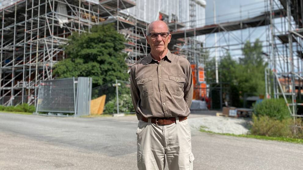 En man som står framför ett hus med byggställningar runt om.