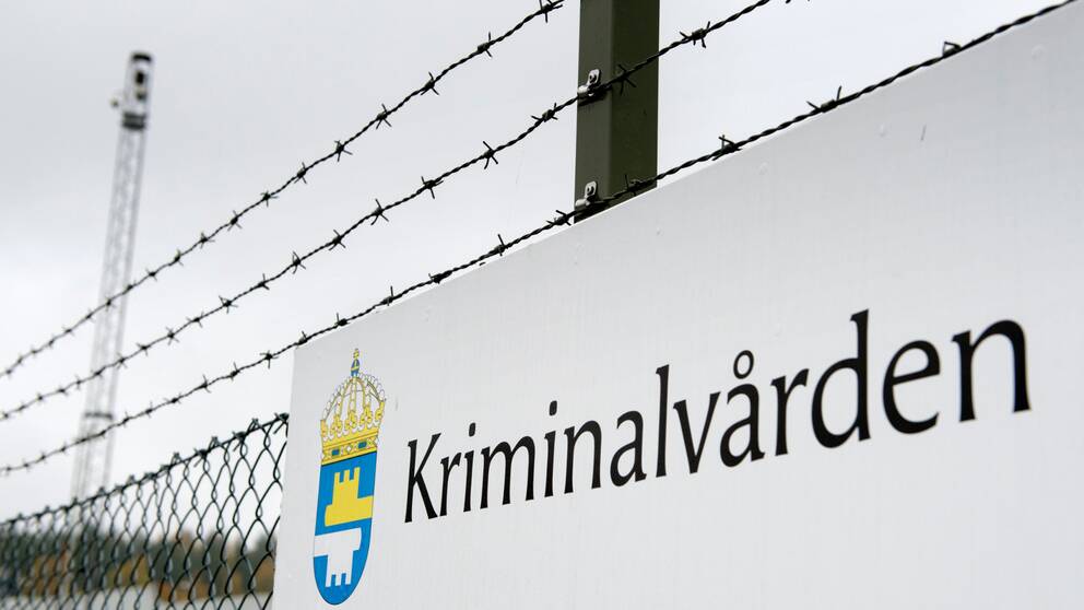 Bild på stängsel runt en av Kriminalvårdens anstalter. På en skylt står det Kriminalvården.