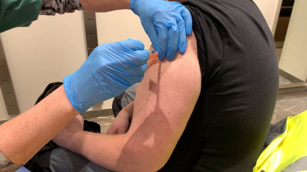 En man som får en vaccinspruta i armen.