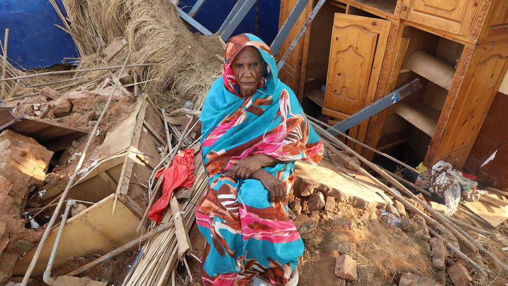 En sudanesisk kvinna sitter på kvarlevorna av sitt hem i delstaten Al Jazirah.