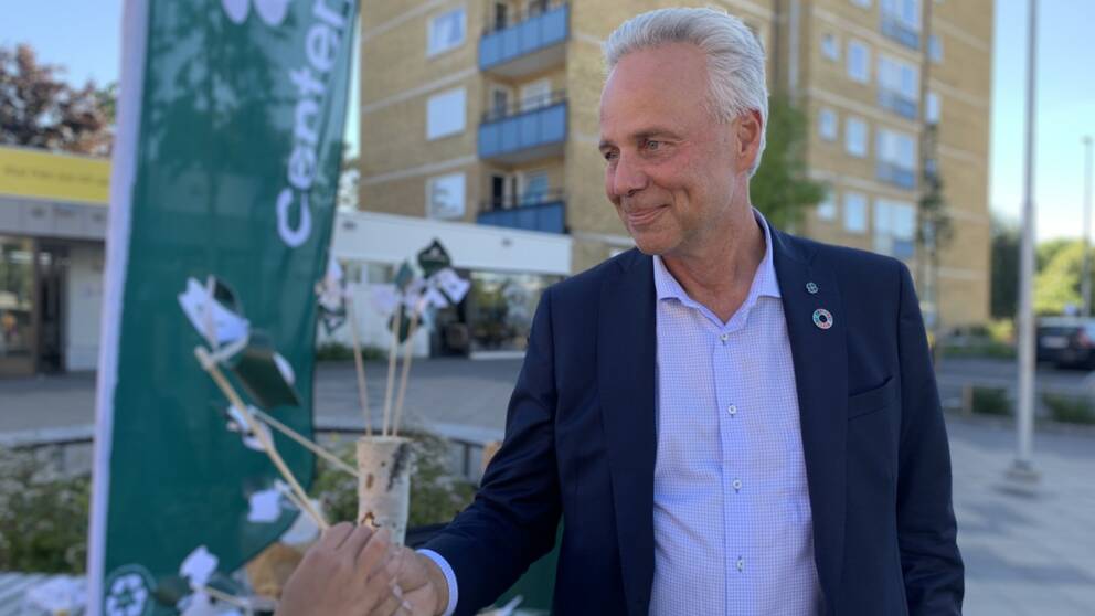 Äldre man valkampanjar och delar ut en flaggor till förbipasserande.