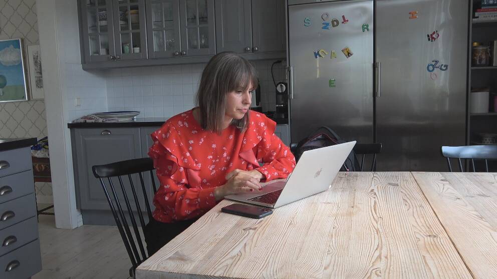 Liza Lundberg sitter framför datorn i sitt kök