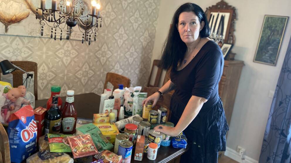 Anneli Widell står vid ett bord fullt av matvaror och hygienprodukter.