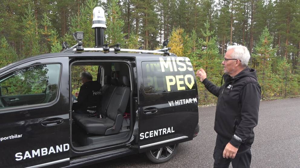 en man med grått hår visar en svart minibuss med ”Missing People”-logotyp och en stolpe med värmekamera monterad på taket