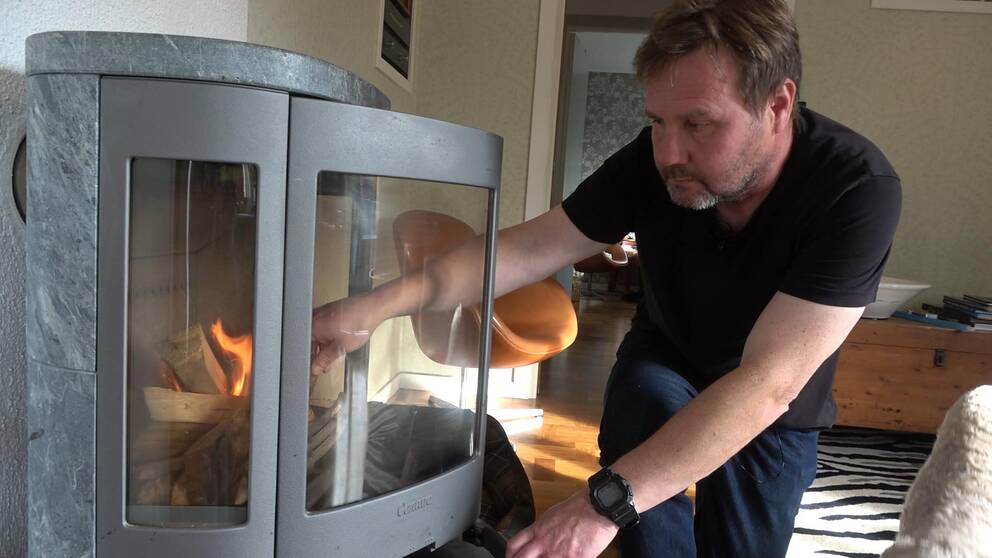 en man som lägger in ved i en kamin i ett vardagsrum