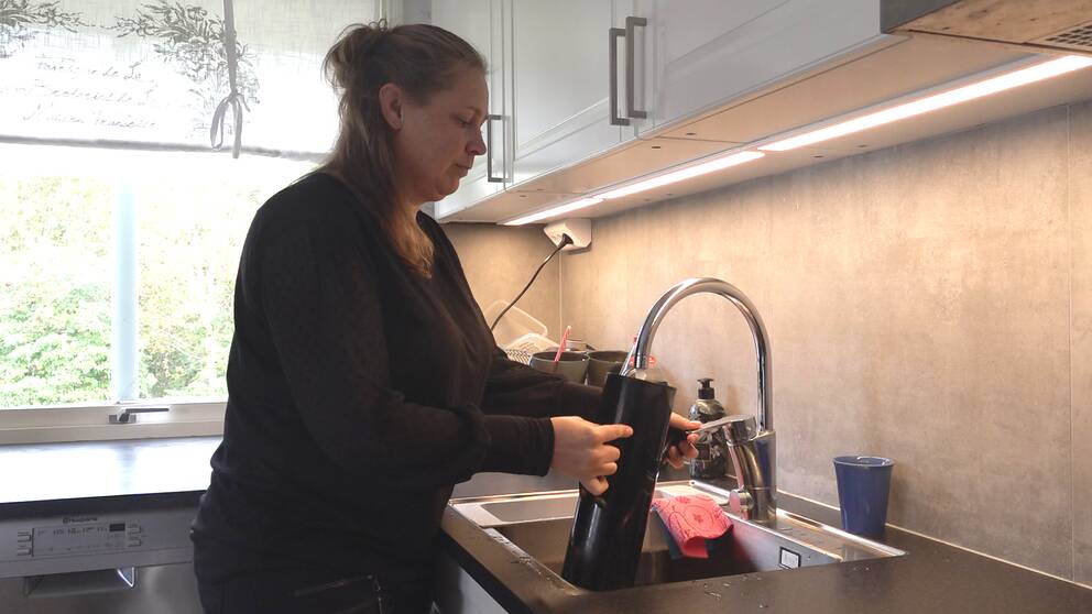 En medelålders kvinna fyller på vatten i en kaffekokare.