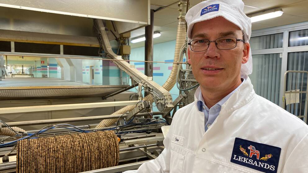 en man med glasögon och leksandsknäcke mössa och kappa – inne i leksands knäckefabriken i Leksand