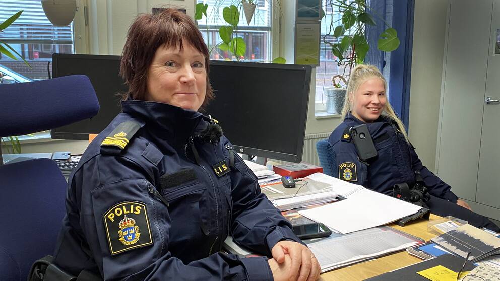Susanne Lindström, områdespolis i Krylbo, sitter till vänster vid ett skrivbord iklädd polisuniform. Till höger sitter Elsa Edvardsson, som snart jobbat som polis i Avesta i ett år. De berättar vad polisen gör för att locka personer i Avesta till polisyrket.