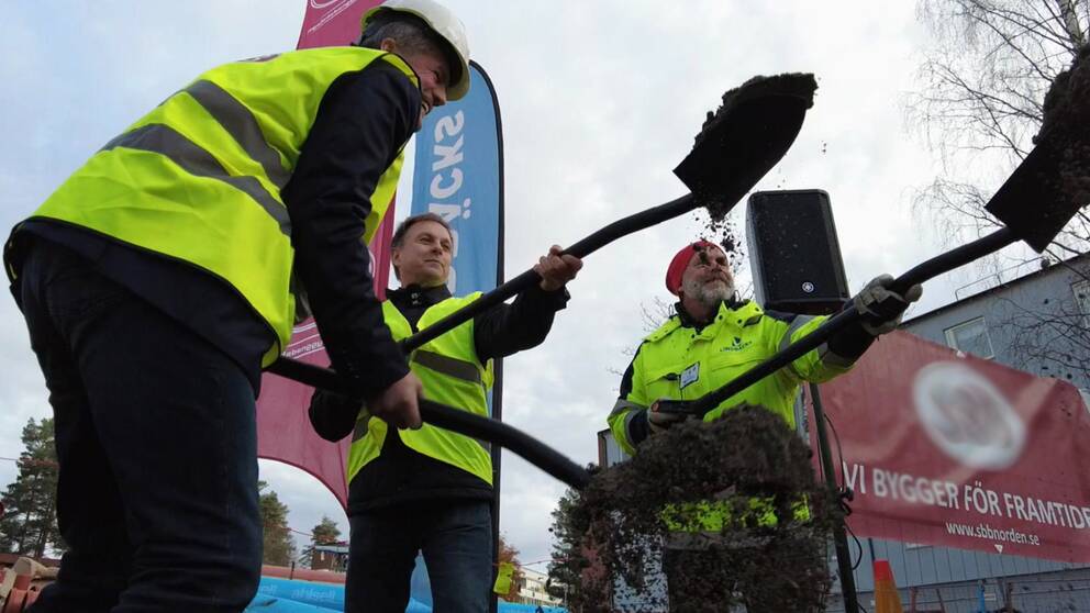På bilden syns hur kommunalrådet Lorents Burman tillsammans med ytterligare två personer tar ”första spadtaget” för starten av bygget av ännu fler lägenheter i Skellefteå.