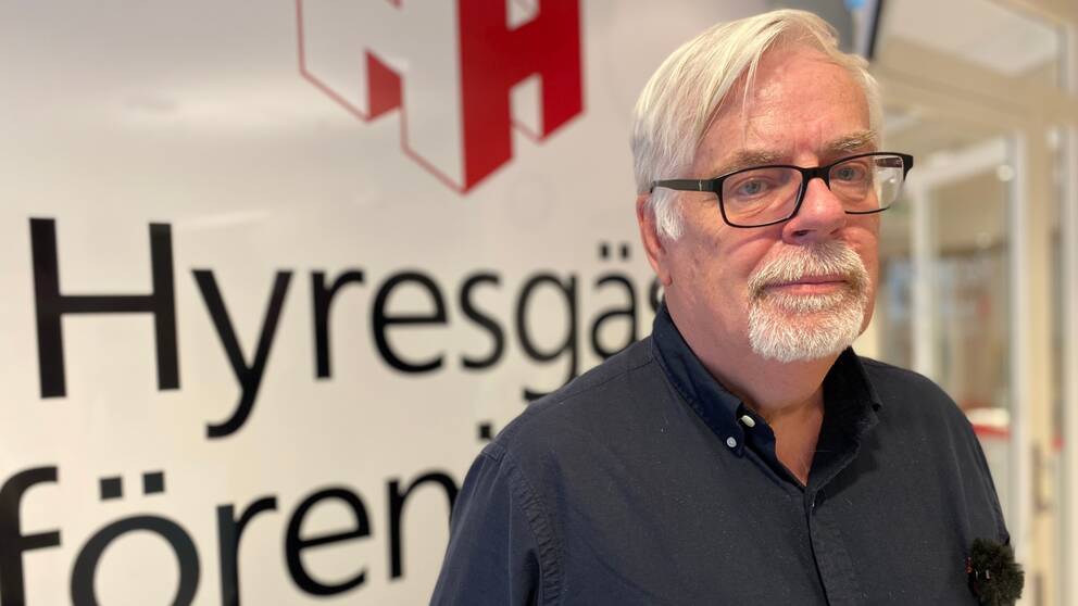 Peter Olsén stående framför Hyresgästföreningens emblem. 