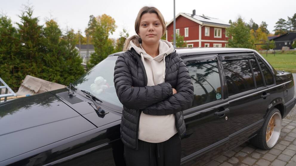 En tonårstjej står framför sin A-traktor.