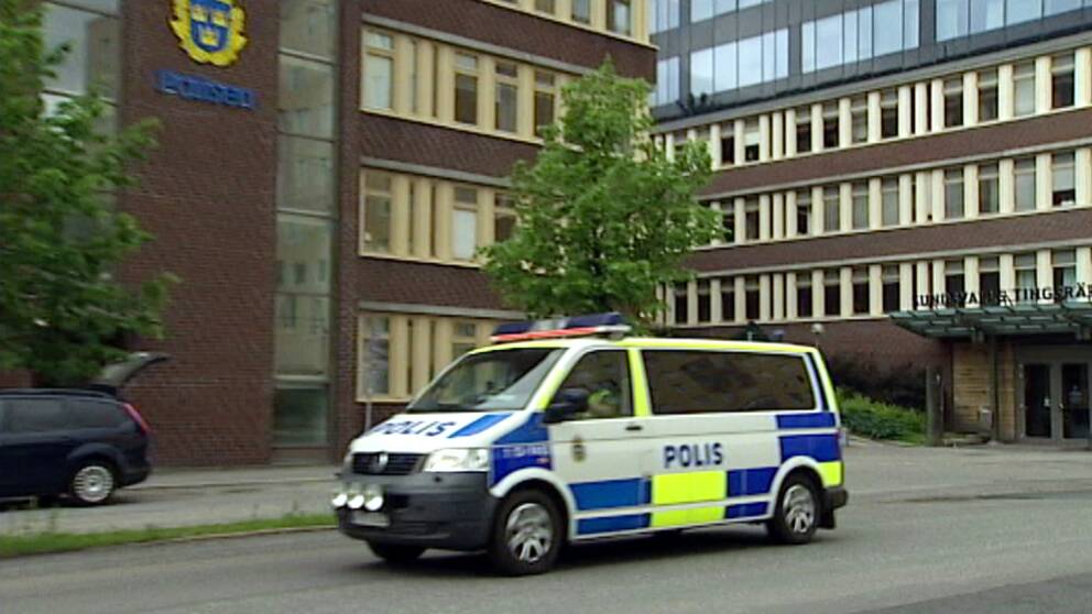 En polisbuss som kör på gatan framför polishuset och Sundsvalls tingsrätt