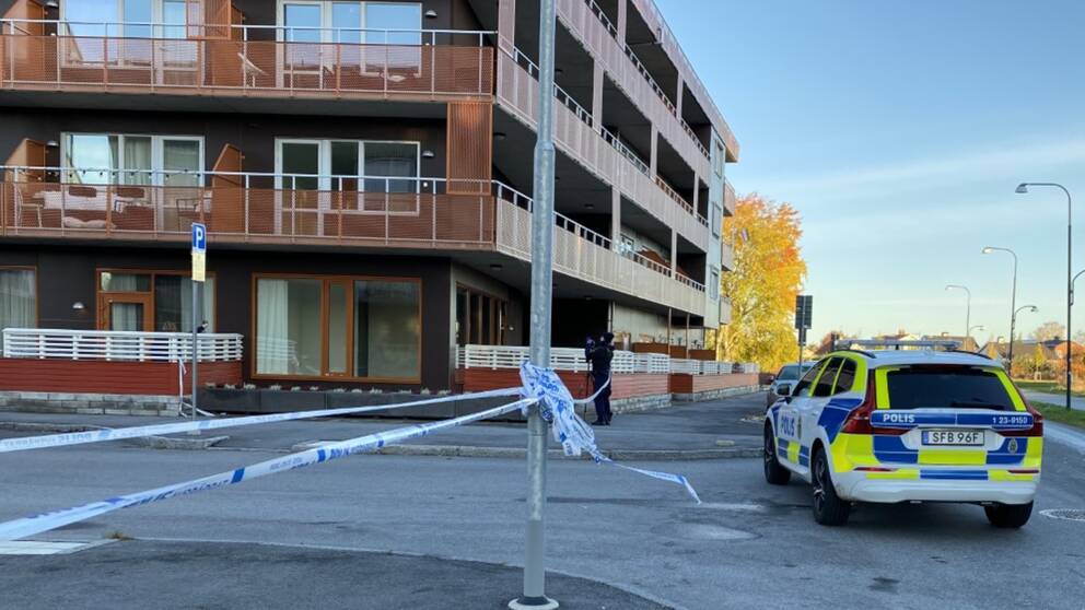 Polisbil och avspärrningsband framför byggnader