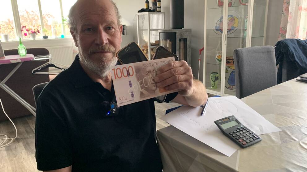 Man som håller i tusenlapp och två mobiltelefoner