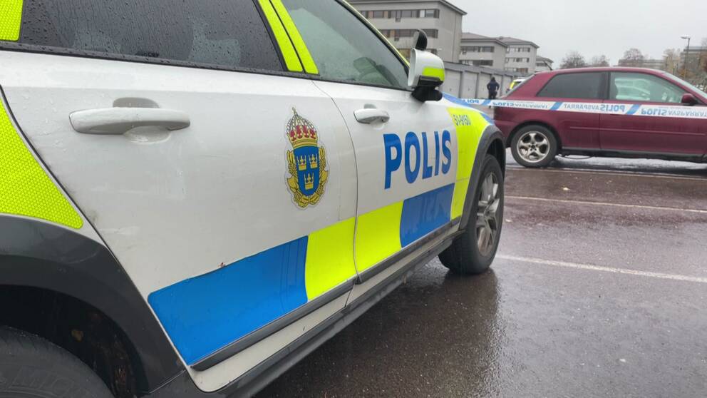 Bild på polisbil och poliser framför garageportar i Gårdsten i Göteborg. Polisen har där spärrat av ett bostadsområde efter att en man hittats medvetslös och skjuten i en bil under tisdagsmorgonen.
