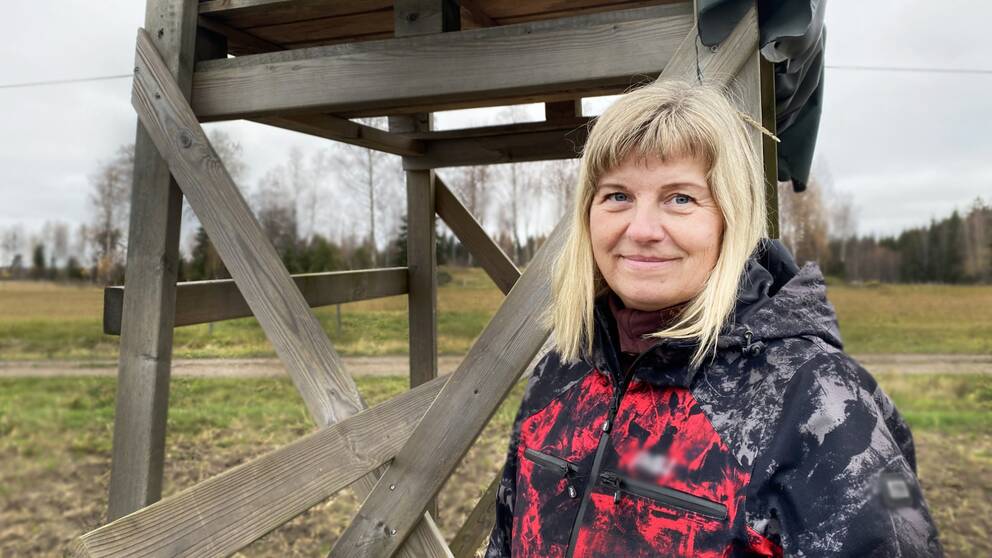 en medelålders kvinna vid ett jakttorn på åkermark