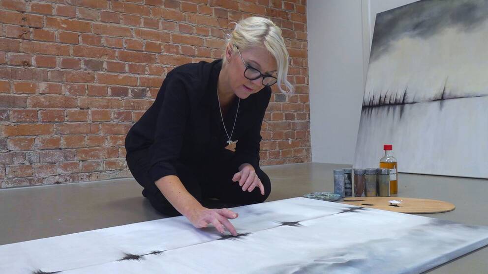 Konstnär Karin Svensson sitter på golvet i sin atelje och skapar sin konst med bara händerna.