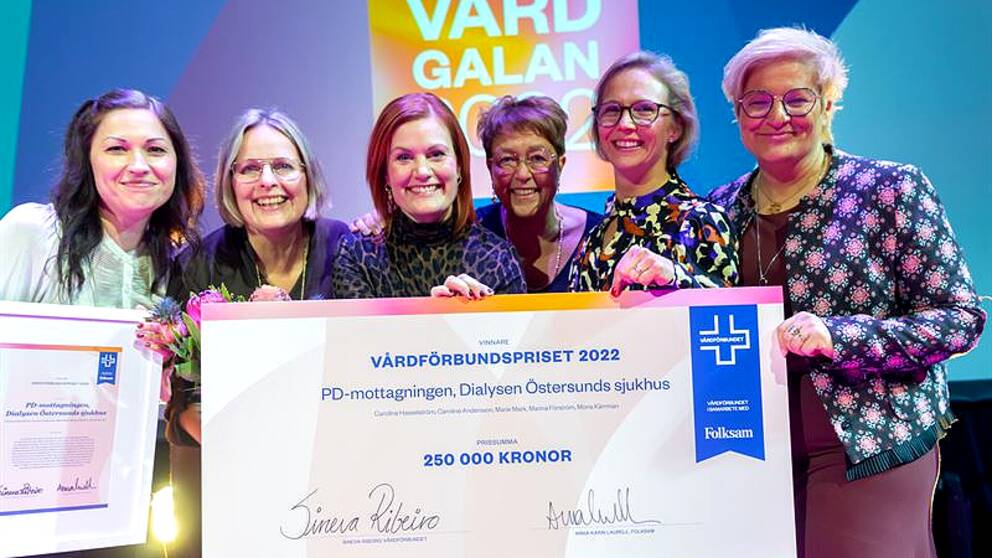 Glada pristagare som håller i en jättestor check på summan 250 000 kronor.