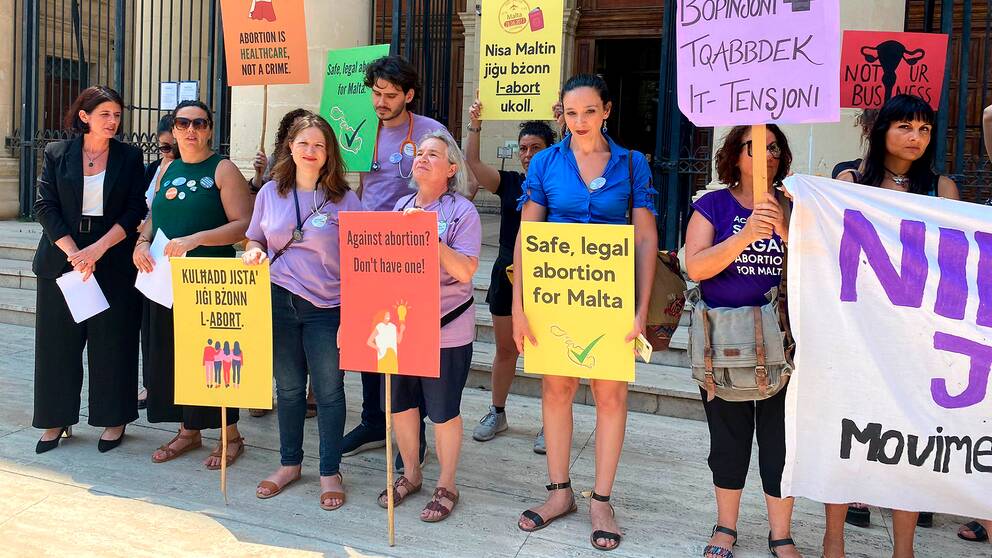 demontranter med skyltar som protesterar mot Maltas abortlagar