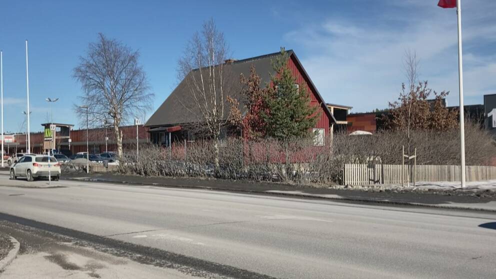 Rött hus med spetsigt svart tak bredvid en asfalterad väg.