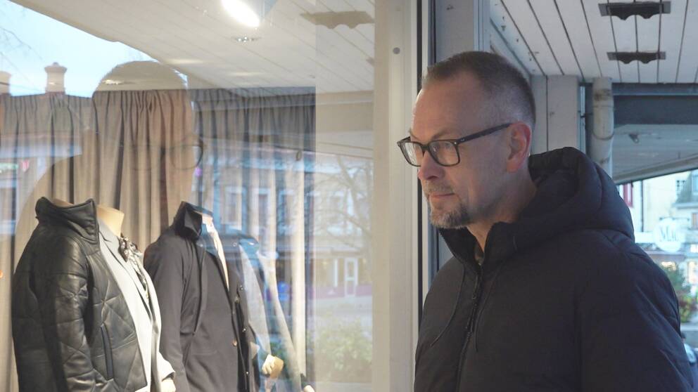 En medelålders man tittar in i ett skyltfönster.