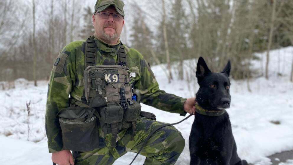 Hundföraren Rickard Wiman sitter med hunden Mila på det militära övningsområdet Kvarn.
