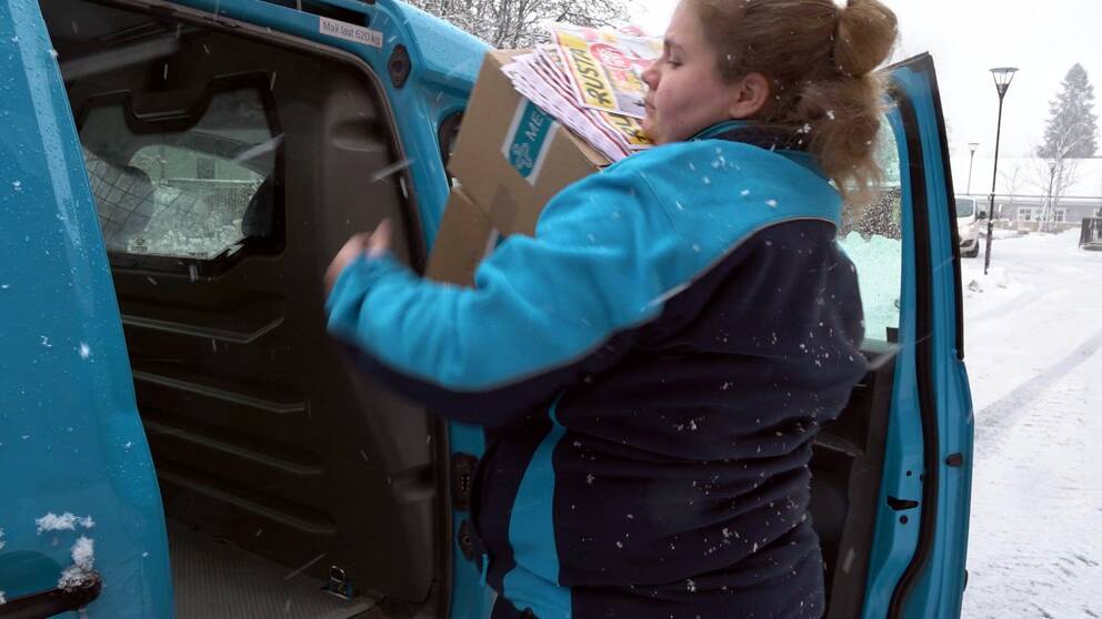 Brevbäraren Jennifer plockar ut paket och post ur sin arbetsbil i snöväder