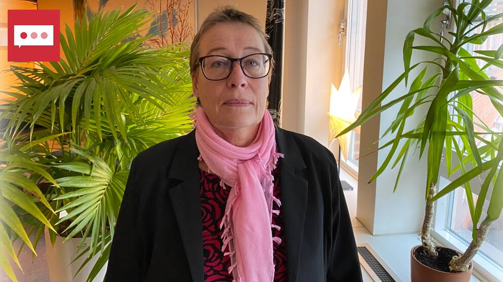 en kvinna med rosa sjal och glasögon. bredvid henne finns flera växter.