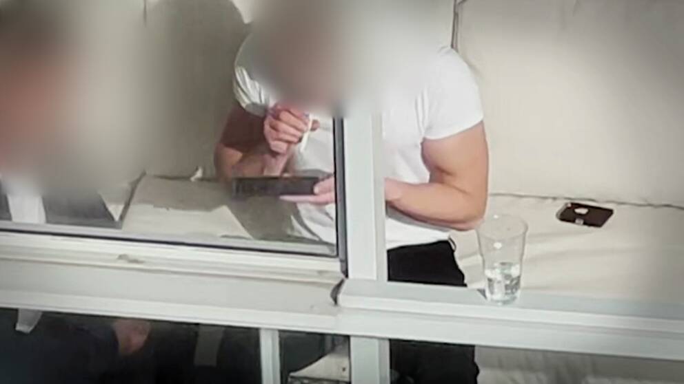 Två anonyma unga personer sitter bakom ett fönster och drar en lina.