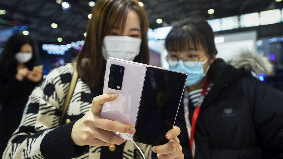 Två kvinnor som kollar in en ny Huawei-telefon.