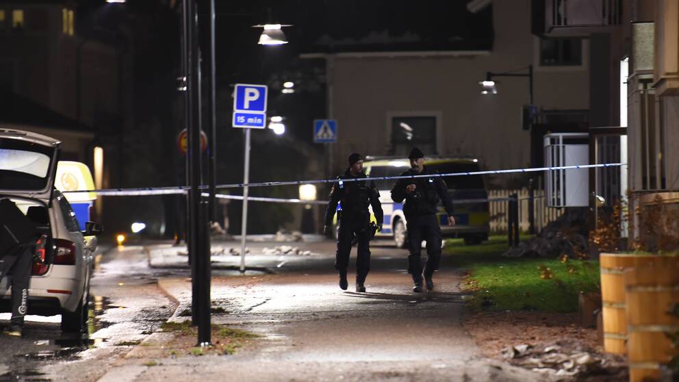Polisband spärrar av utanför ett höghus, och två poliser går innanför avspärrningen.