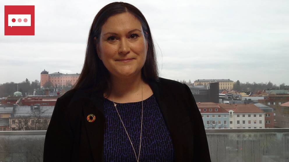 en kvinna i kavaj framför en stadsvy över Uppsala