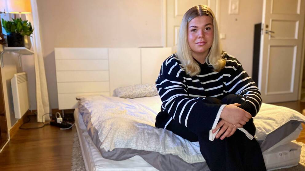 Bild på Filippa Andersson som sitter på madrassen där hon sover hos sina föräldrar med anledning av att det är bostadsbrist i Skellefteå och hon inte har tillräckligt många köpoäng för att få ett hyreskontrakt.