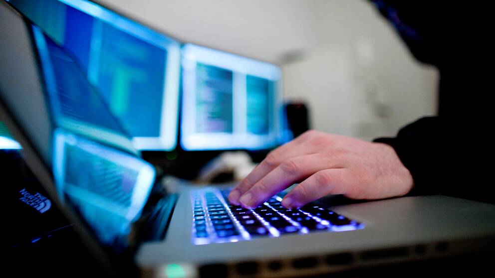 En bild på datorer en hand som skriver något på ett tangentbord.