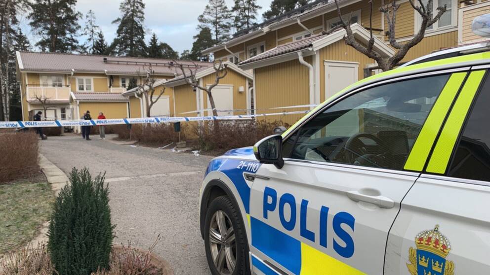 En polisbil med hus i bakgrunden.
