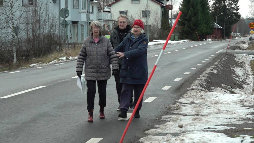 Två kvinnor och en man, boende i Ambjörb, går på vägen för att gång- och cykelvägen är försenad.