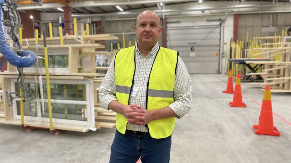 Peter Rhensbo, vd på Norrlands trähus, står i en lagerlokal med brädor i bakgrunden och berättar om den ekonomiskt svåra situationen för hans företag.