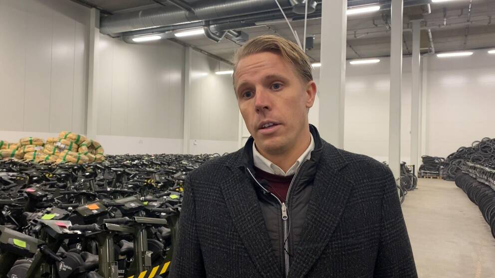 Daniel Mohlin, manager på företaget Inurba Mobility, står i en lagerlokal framför hundratals parkerade elcyklar.