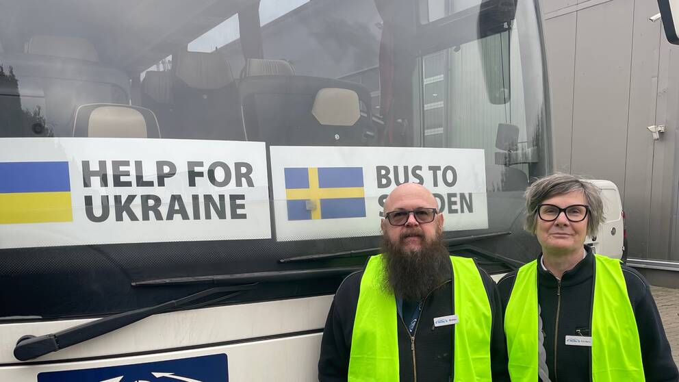Bild på en man och en kvinna i var sin varselväst framför en buss med skyltar där det står Help for Ukraine och Bus to Sweden. Personerna heter Bobbo Nilsson och Rose-Marie Östergren och körde andra bussen med ukrainska flyktingar från Polen till Sverige